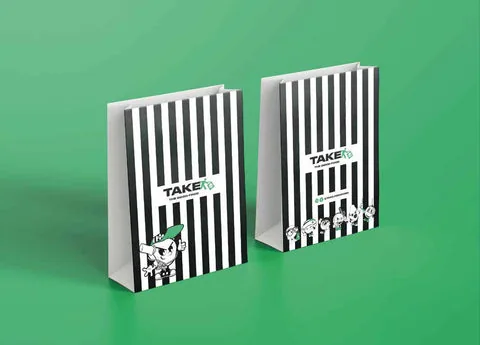 Twee zwart-wit gestreepte papieren tassen met het logo van TAKE en de stripfiguren van het merk